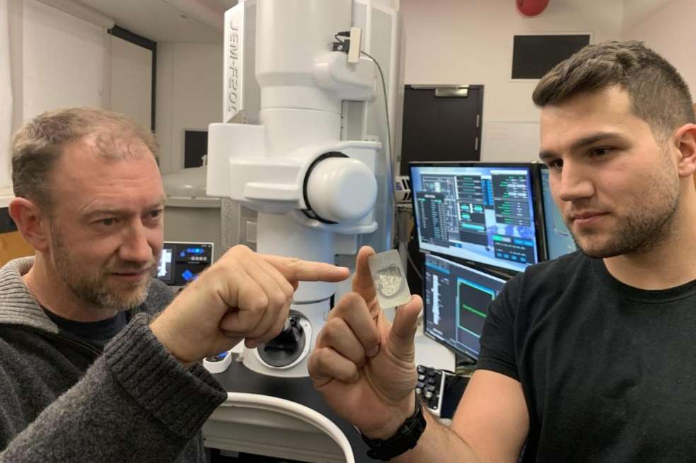 El profesor de la Universidad de Monash Andy Tomkins (a la izquierda) con el becario de doctorado de la Universidad RMIT Alan Salek sosteniendo una muestra de meteorito de ureilita en las instalaciones de microscopía y microanálisis de la RMIT