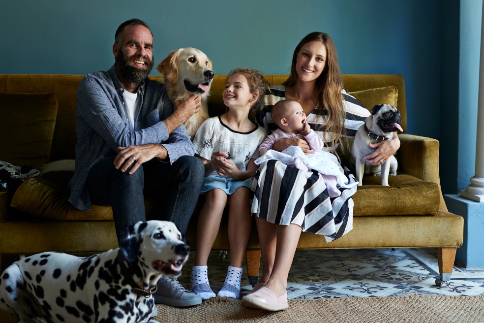 Una linda familia: papá, mamá, dos hijos y tres perros en la sala de una casa.