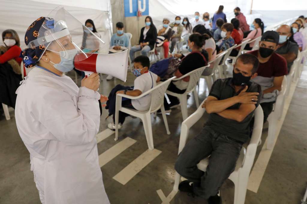 AME6413. BOGOTÁ (COLOMBIA), 17/02/2022.- Una enfermera da instrucciones a personas que esperan para vacunarse contra la covid-19, el 16 de febrero de 2022 en Bogotá (Colombia). La campaña de vacunación contra la covid-19 en Colombia, que comenzó lentamente y después que en la mayoría de países latinoamericanos, superó en un año los obstáculos burocráticos y geográficos para reducir sustancialmente las muertes y hospitalizaciones por coronavirus. EFE/Carlos Ortega