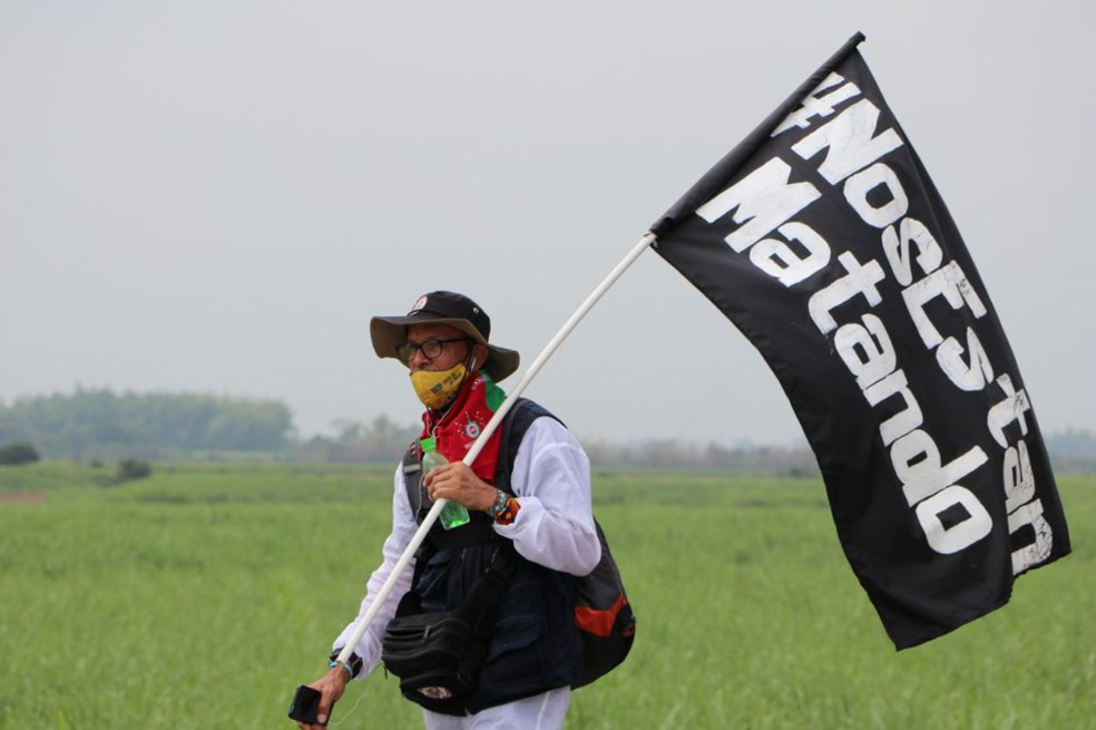 Un hombre lleva una bandera que dice: "Nos están matando".