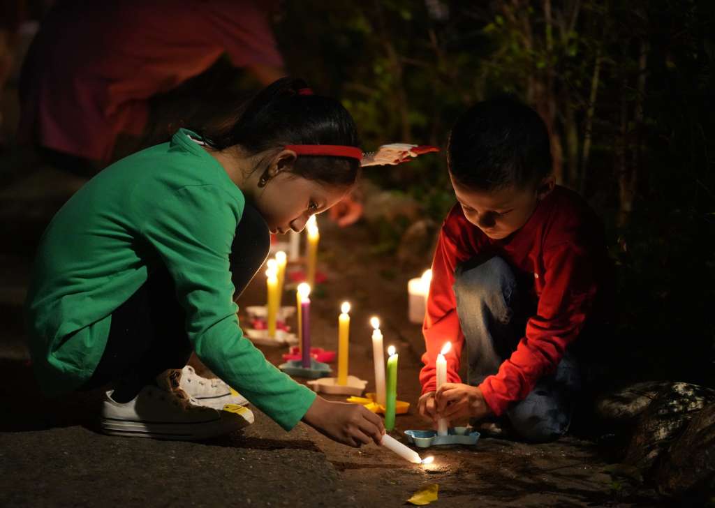 AME4025. CALI (COLOMBIA), 07/12/2024.- Dos niños encienden velas durante la tradicional Noche de las Velitas este sábado en Cali (Colombia). La tradicional Noche de las Velitas, que marca el inicio de la Navidad en Colombia, se vivió este sábado en el que familias a lo largo y ancho del país se reunieron en viviendas, edificios, plazas y parques para compartir comida y golosinas y disfrutar de los alumbrados navideños. EFE/Ernesto Guzmán