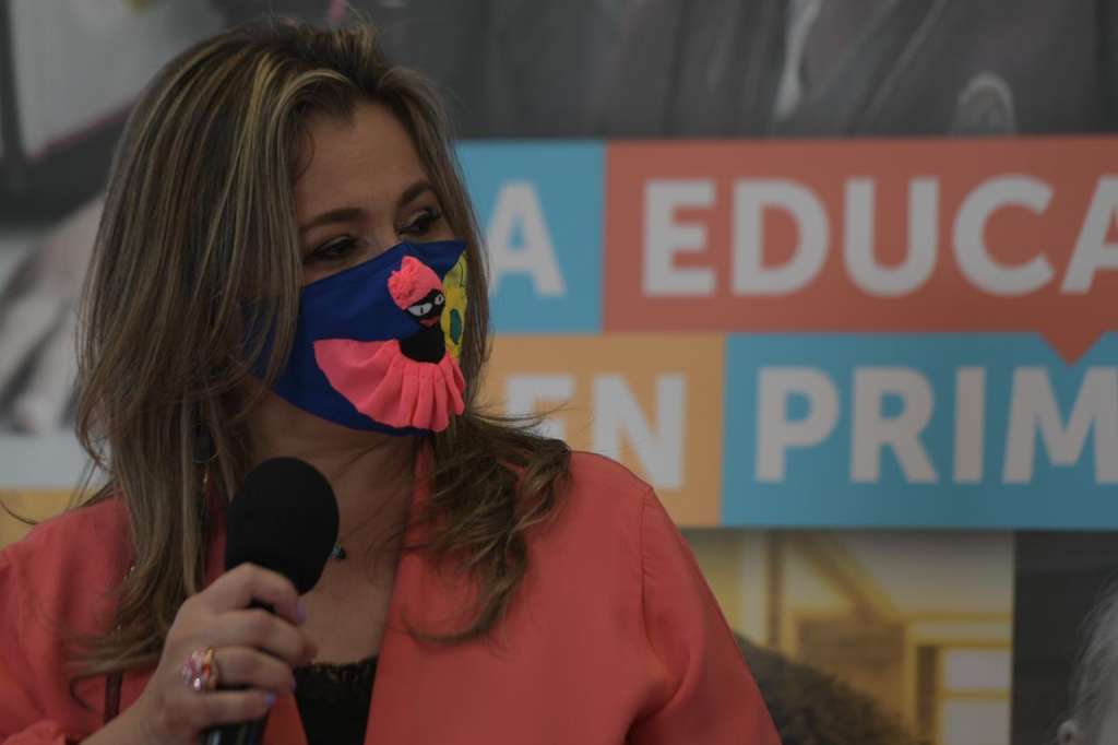 Edna Bonilla con tapabocas y un micrófono en la mano derecha