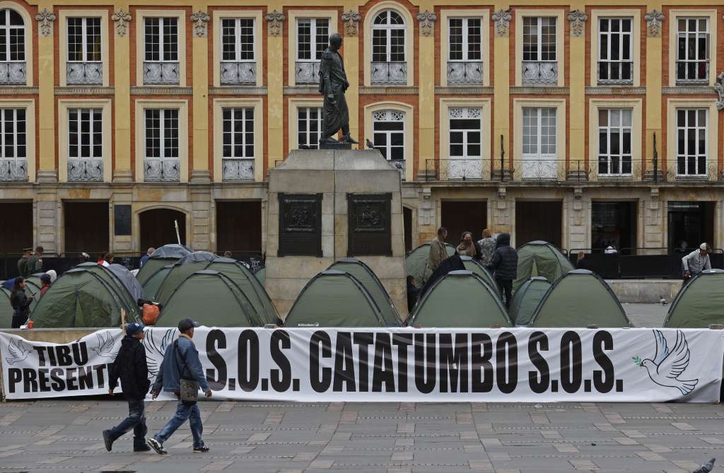 AME4968. BOGOTÁ (COLOMBIA), 29/01/2025.- Personas caminan frente a un campamento de líderes campesinos de la región del Catatumbo este miércoles, en la Plaza de Bolívar en Bogotá (Colombia). La violencia generada por los enfrentamientos entre la guerrilla del Ejército de Liberación Nacional (ELN) y el Frente 33 de las disidencias de las FARC ha causado el desplazamiento de más de 40.000 personas. EFE/ Mauricio Dueñas Castañeda