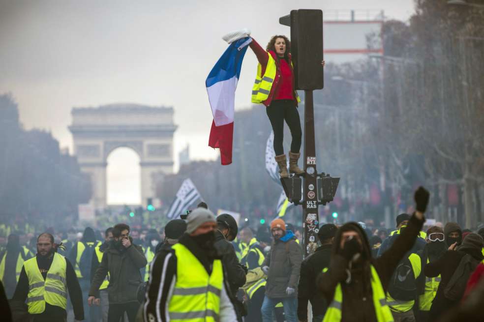 El excampeón de boxeo francés Chistophe Dettinger (derecha- vestido con gorro negro) patea a un miembro del Cuerpo de Gendarmería durante una manifestación de los "chalecos amarillos" en París, Francia, 5 de enero de 2018. / EFE