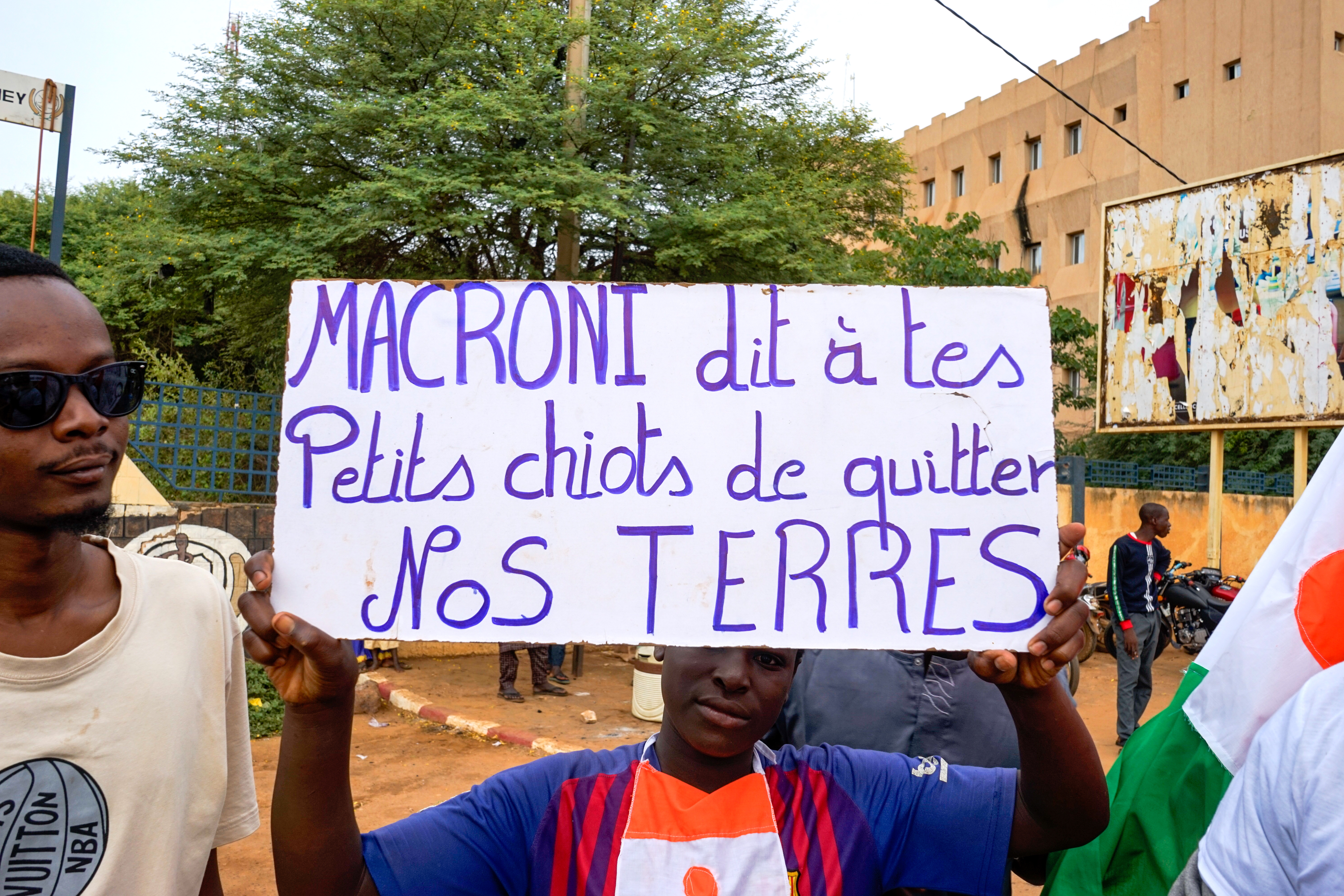 Niamey (Niger), 20/08/2023.- A supporter of the military junta displays a sign that reads 'Macron, tell your puppies to leave our land' during a protest against a potential military intervention in Niamey, Niger, 20 August 2023. The coup leader, General Abdourahmane Tchiani, warned against a military intervention after the ECOWAS leaders said they were 'Äòready to go'Äô and reinstall democratically elected Niger President Mohamed Bazoum. (Protestas, Golpe de Estado) EFE/EPA/ISSIFOU DJIBO