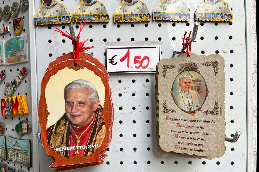 GRAF1960. CIUDAD DEL VATICANO, 03/01/2023.- Algunos suvenires que retratan al papa emérito Benedicto XVI en las tiendas que rodean el Vaticano. Las leyes del libre mercado afectan hasta a las cuestiones más sacras y cientos de tiendas hacen el agosto al calor del Vaticano vendiendo recuerdos y minucias con cada evento pontificio. Sin embargo, la muerte de Benedicto XVI pasa sin pena ni gloria por sus estanterías. Es el papa sin suvenires. EFE/ Gonzalo Sánchez