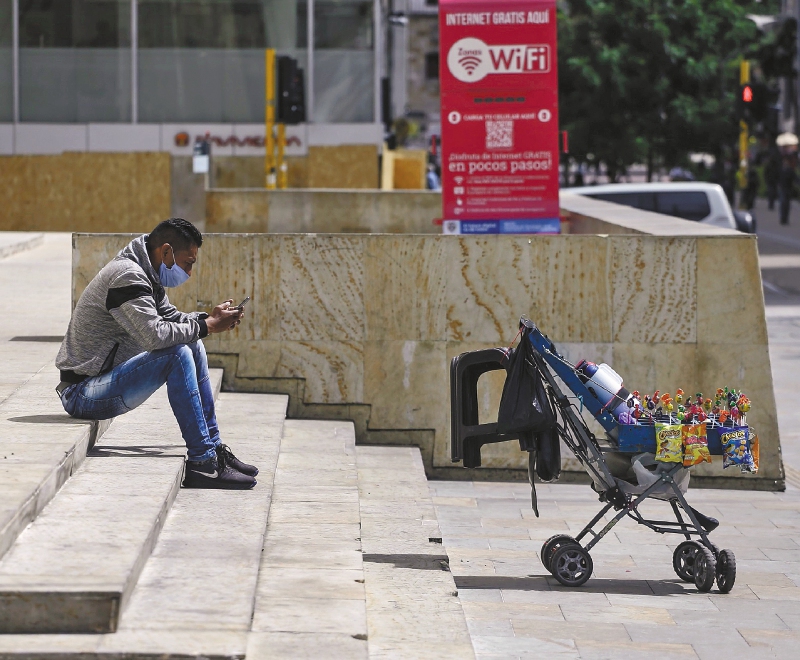A street vendor wearing a protective mask looks at a smartphone as he waits for customers during a national strike in Bogota, Colombia, on Monday, Sept. 21, 2020. Nationwide marches are scheduled for Monday to protest, among others, police brutality and the murder of social leaders. Photographer: Ivan Valencia/Bloomberg