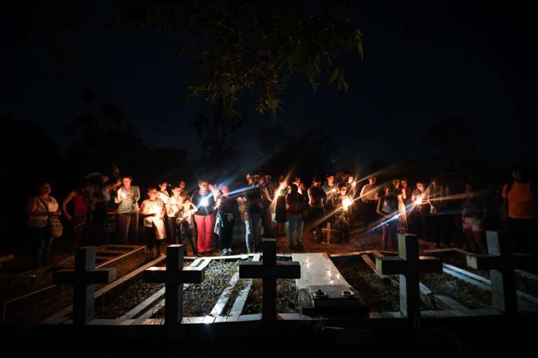 un grupo de personas se encuentran en un evento simbólico con velas.