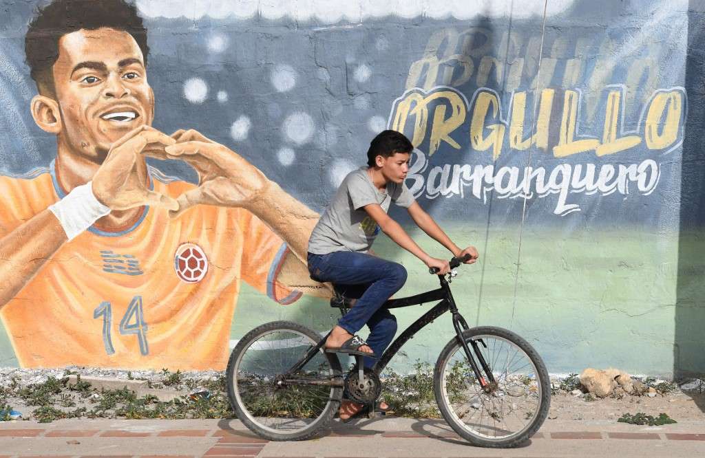 Un joven monta en bicicleta frente a un mural que representa a la estrella del fútbol del Liverpool de Inglaterra, el colombiano Luis Díaz, en Barrancas, departamento de la Guajira.
