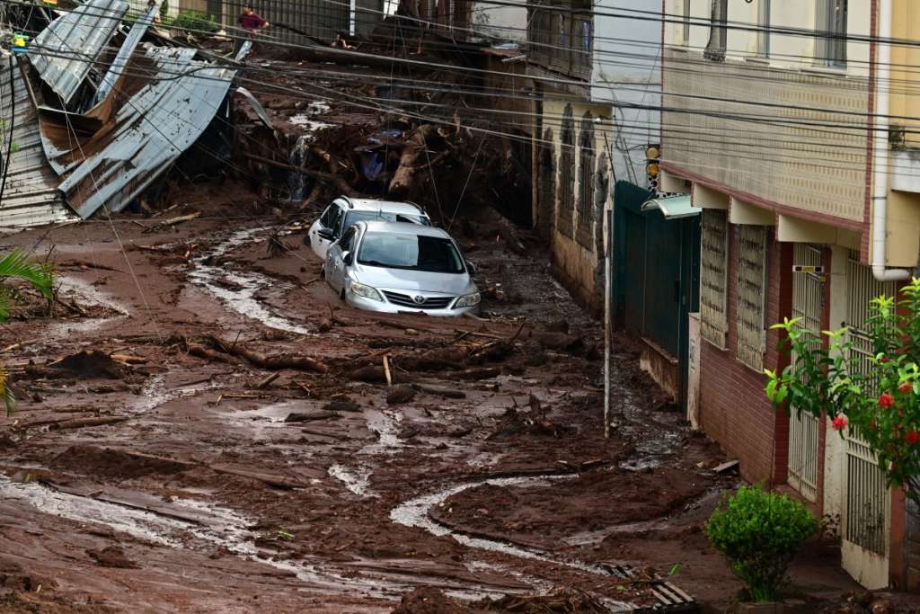 Vehicles are partially covered in mud after a landslide triggered by heavy rains in the Paineiras neighborhood in Juiz de Fora, Minas Gerais State, Brazil, on February 25, 2026. In a climate of despair, rescuers and residents searched on February 25 for 33 people still missing after torrential rains swept southeastern Brazil, leaving 36 dead, according to a new official toll. (Photo by Pablo PORCIUNCULA / AFP)