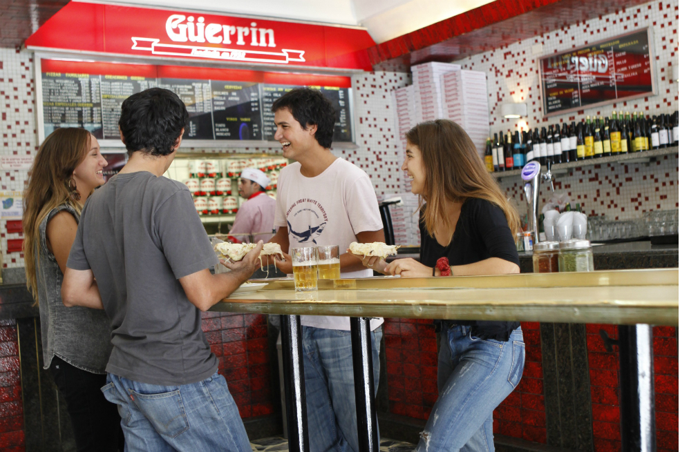 Güerrín: esta famosa pizzería, que nació hace más de 80 años, cuenta con 70 variedades disponibles y es un paraíso para los amantes de la pizza al molde. Su masa se trabaja todavía en forma manual en una gran batea, a pesar de la asombrosa cantidad de pizzas despachadas a lo largo del día. Ubicada en Av. Corrientes al 1368, es el lugar ideal para disfrutar después de tu obra de teatro elegida.El Palacio de la Papa Frita: este clásico reducto porteño ubicado en Corrientes al 1612, ofrece desde 1952 jugosos bifes de chorizo de novillo de exportación, asado de tira de siete costillas, y unas papas fritas soufflé deliciosas, infladas como zeppelines. ¿El secreto del éxito? El corte de la papa, la mezcla del aceite y la fritura en tres temperaturas distintas ¡Imperdible para vivir una completa experiencia porteña!