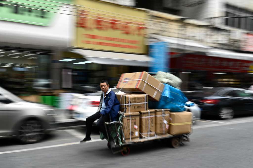 TOPSHOT - This photo taken on February 18, 2025 shows a man transporting boxes of merchandise on an electric platform at a commercial area in Dongguan, China's southern Guangdong province.