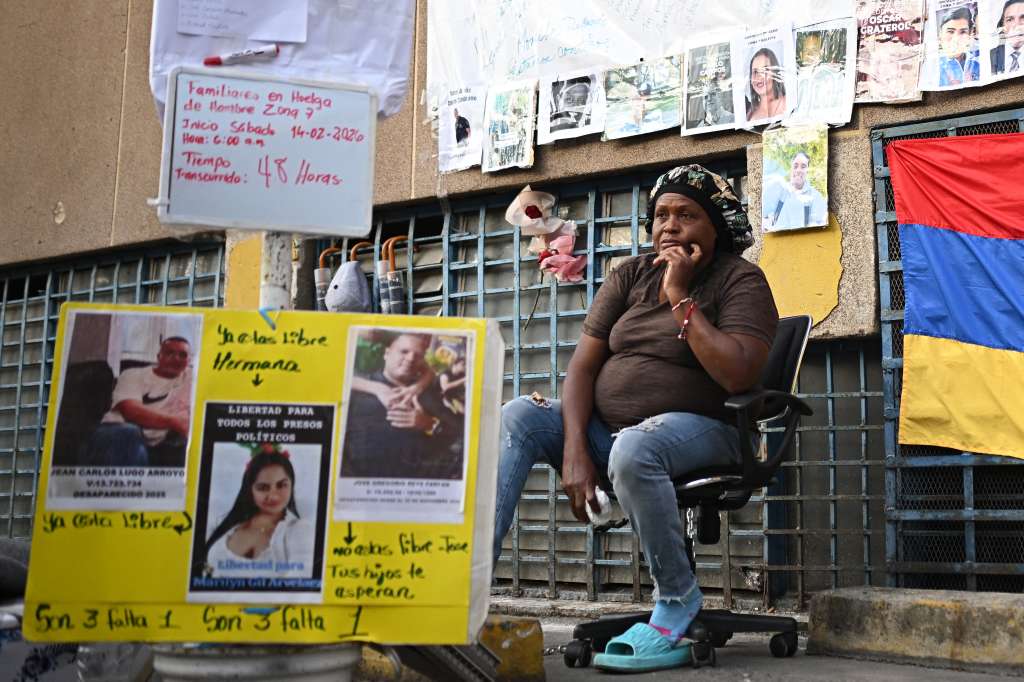 A relative of a political prisoner sits on a chair during a hunger strike outside of the Bolivarian National Police (PNB) Zone 7 prison in Caracas on February 16, 2026. A dozen relatives of political prisoners began a hunger strike on February 14 to press for more releases, following the postponement two days ago of the approval of a historic amnesty law. (Photo by Federico PARRA / AFP)