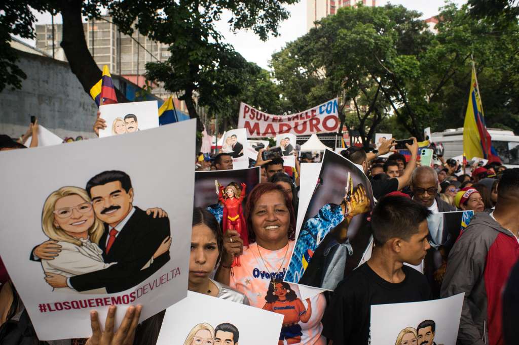 AME4053. CARACAS (VENEZUELA), 10/01/2026.- Personas sostienen carteles durante una manifestación este sábado, en Caracas (Venezuela). Simpatizantes chavistas se movilizaron en distintas zonas de Caracas y en varias regiones de Venezuela para exigir a Estados Unidos la liberación y el regreso del mandatario Nicolás Maduro y su esposa, la diputada Cilia Flores, capturados hace una semana por fuerzas del país norteamericano en medio de una serie de ataques. EFE/ Boris Vergara