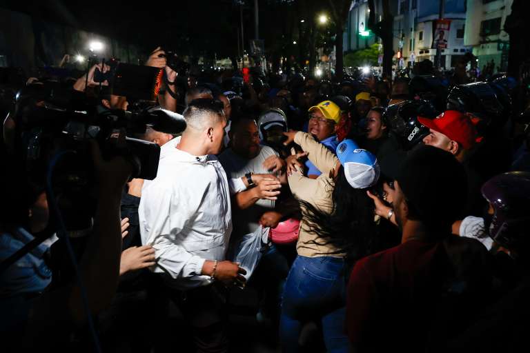 AME5913. CARACAS (VENEZUELA), 28/07/2024.- Seguidores del presidente de Venezuela y candidato a la reelección, Nicolás Maduro, bloquean el acceso a personas que intentan entrar a un centro de votación para el conteo de votos este domingo, en Caracas (Venezuela). Varias decenas de motorizados que se identificaron como chavistas llegaron a un centro de votación en Caracas, donde se encontraban testigos opositores y ciudadanos que esperaban el comienzo del escrutinio de las elecciones presidenciales de este domingo, lo que dio lugar a una confrontación que acabó a golpes, ante la mirada impasible de los policías, que no intervinieron para detener la pelea. EFE/ Henry Chirinos
