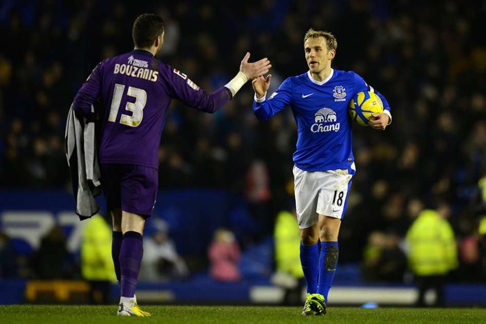 Phil Neville del Everton se saluda con Dean Bouzanis, arquero del Oldham. / AFP