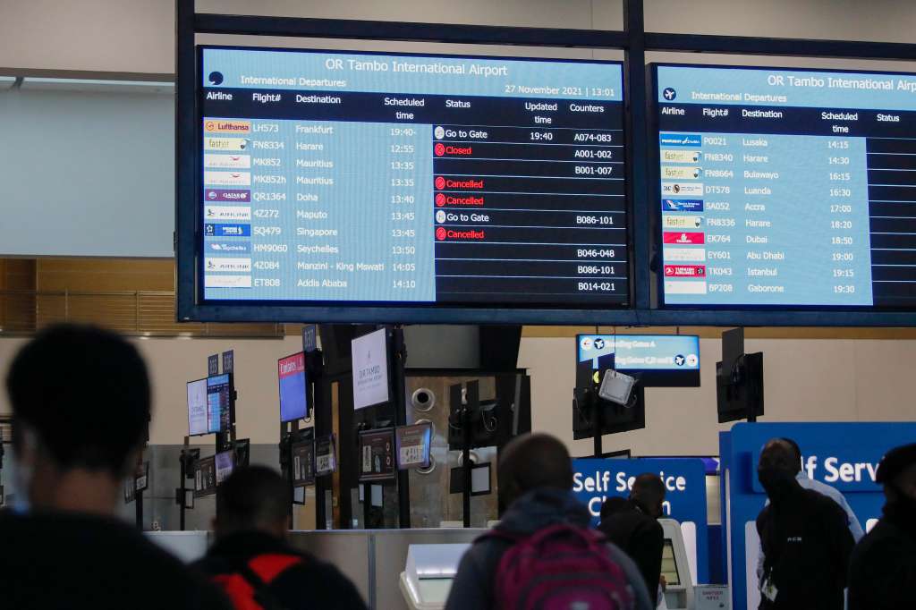 Los viajeros caminan cerca de un tablón de anuncios de vuelos electrónico que muestra vuelos cancelados en el Aeropuerto Internacional en Johannesburgo el 27 de noviembre