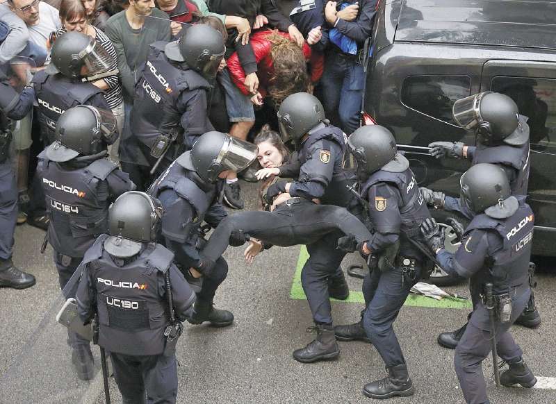 La policía española detiene a una joven enfrente de uno de los puestos de votación en Barcelona. / EFE