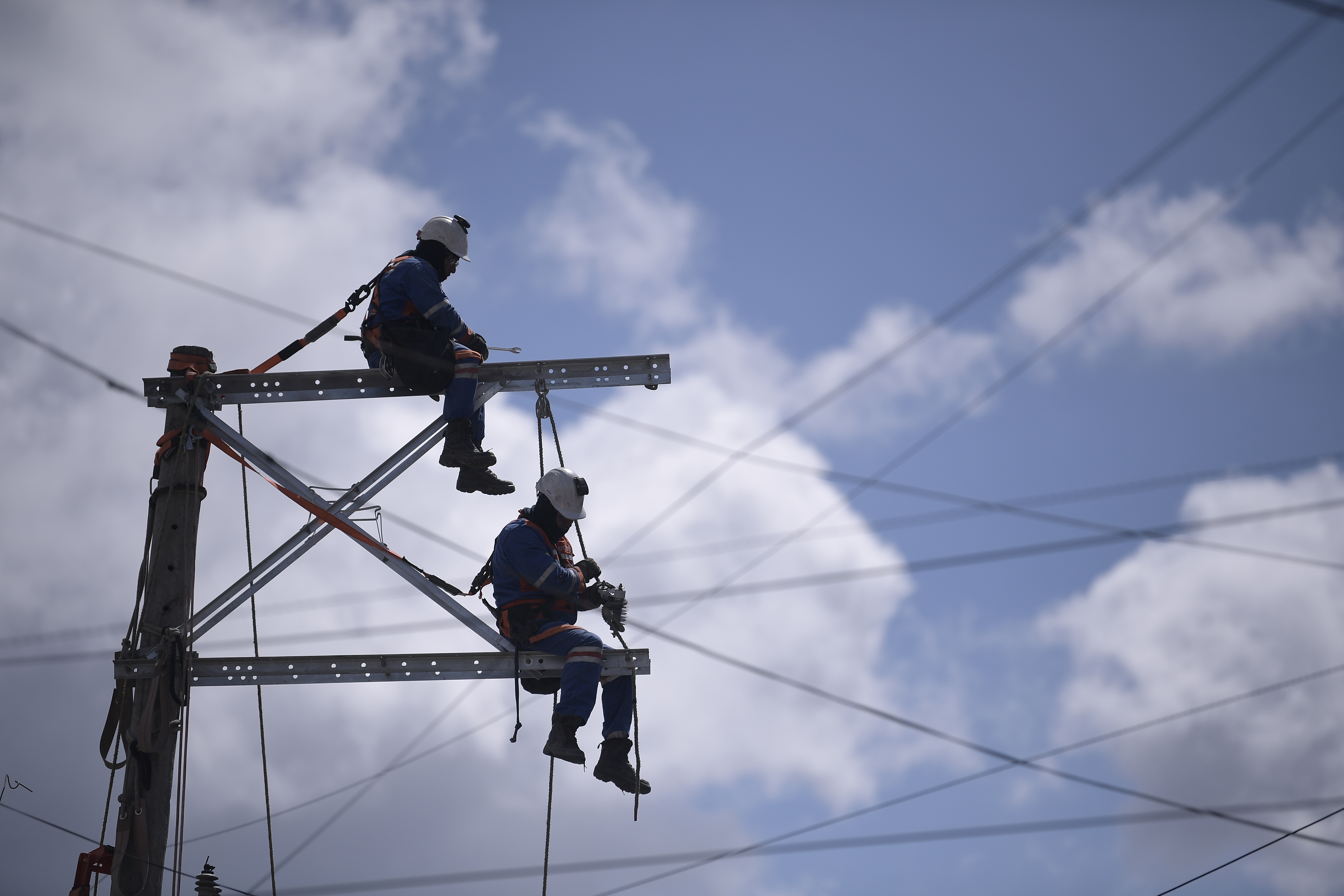 Hombres trabajando en un poste de energía eléctrica.