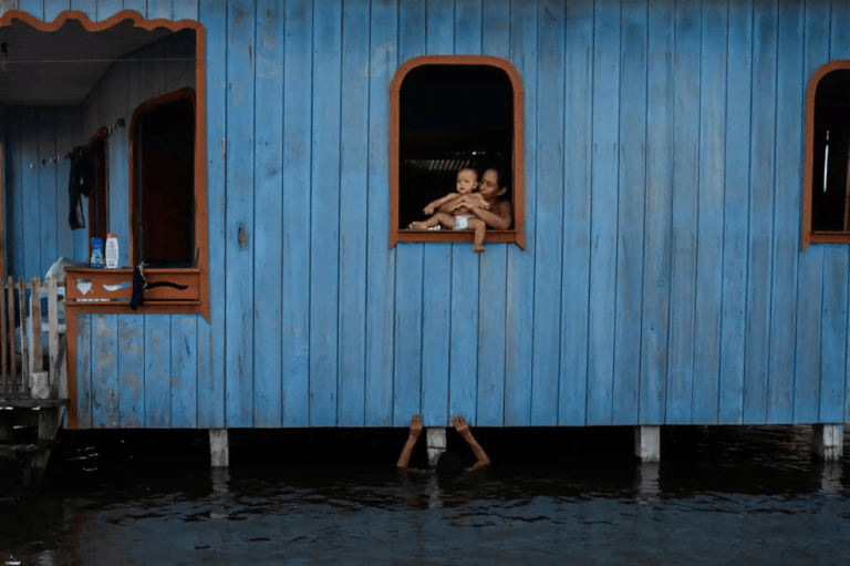 Categoría clima:
Raphael Alves capturó el momento en que una mujer observa, desde la ventana de su casa, a su hijo jugar en la crecida de los ríos, en Anama, Brasil.