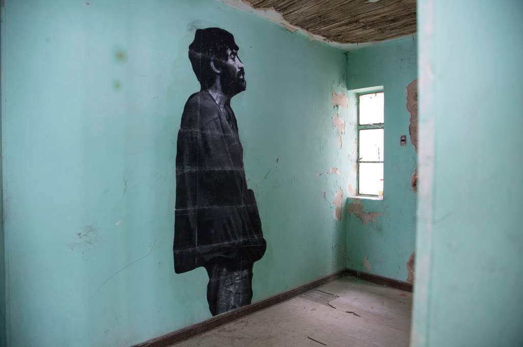 Una foto en blanco y negro de un hombre pegada en una pared verde.