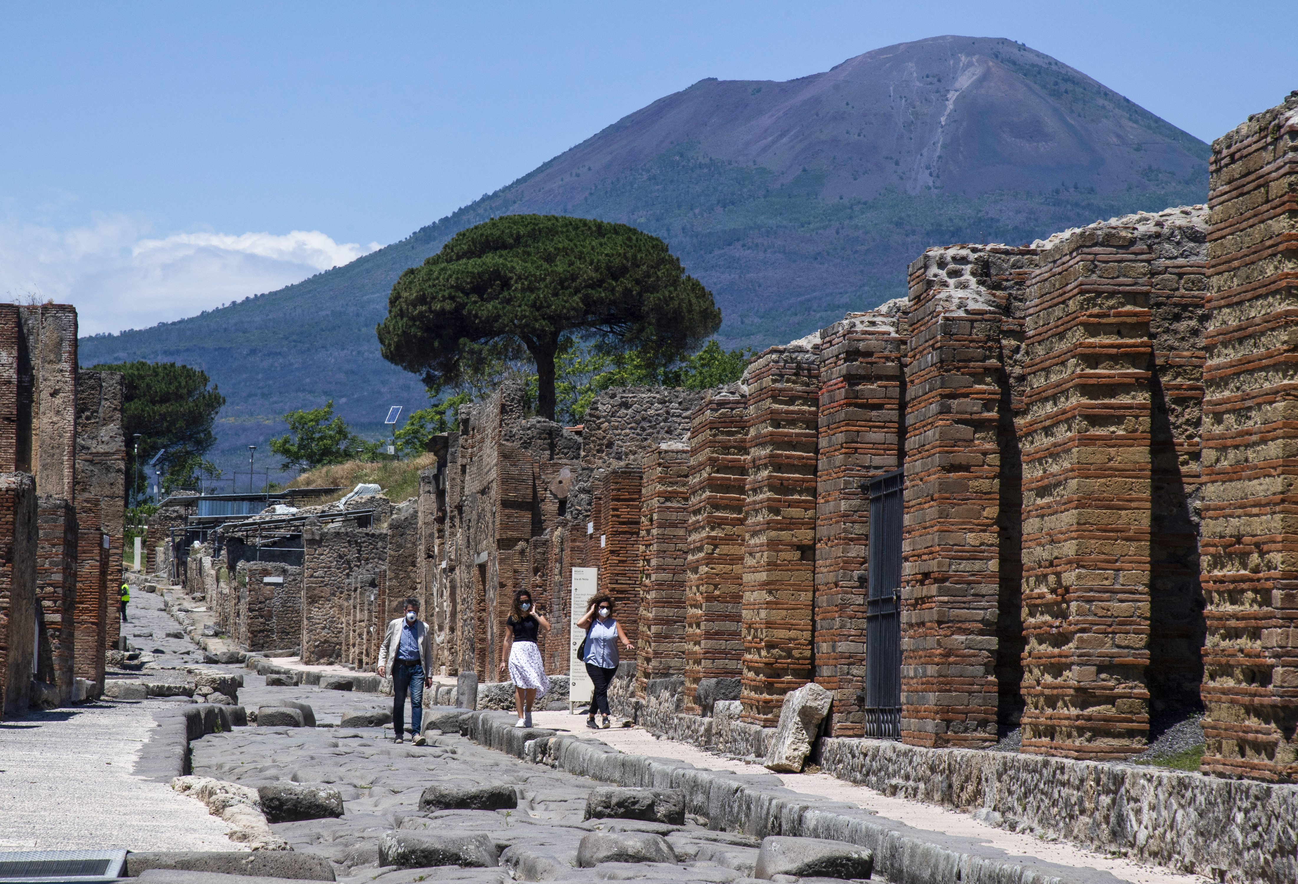 (FILES) Visitors walk across the archeological site of Pompeii at the bottom of the Mount Vesuvius volcano (Rear) on May 26, 2020, as the country eases its lockdown aimed at curbing the spread of the COVID-19 infection, caused by the novel coronavirus.