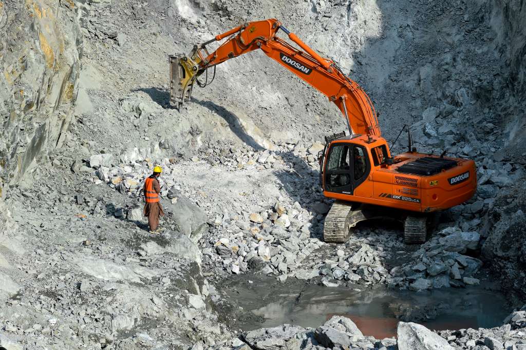 This photograph taken on January 18, 2025 shows an Afghan worker standing next to an excavator at a Nephrite mine in the mountains of Goshta district, Nangarhar province.