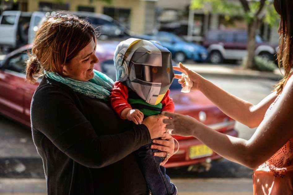 Una mujer sostiene a su hijo, que lleva un casco característico del dúo francés de música electrónica Daft Punk, en la localidad de Wee Waa, en Australia.