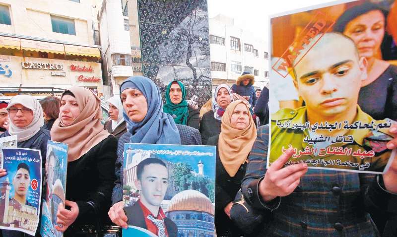 Manifestantes sostienen afiches con los rostros de Abdul Fatah al-Sharif (izquierda) y Elor Azaria (derecha). / AFP