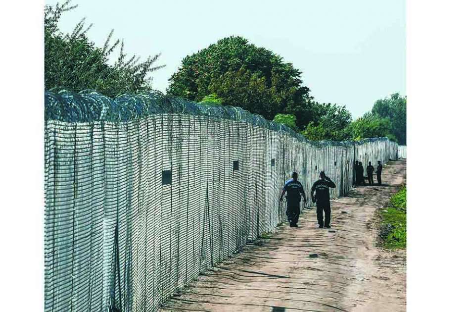 La policía patrulla la valla alambrada que el gobierno húngaro instaló para evitar el paso de más refugiados. / AFP