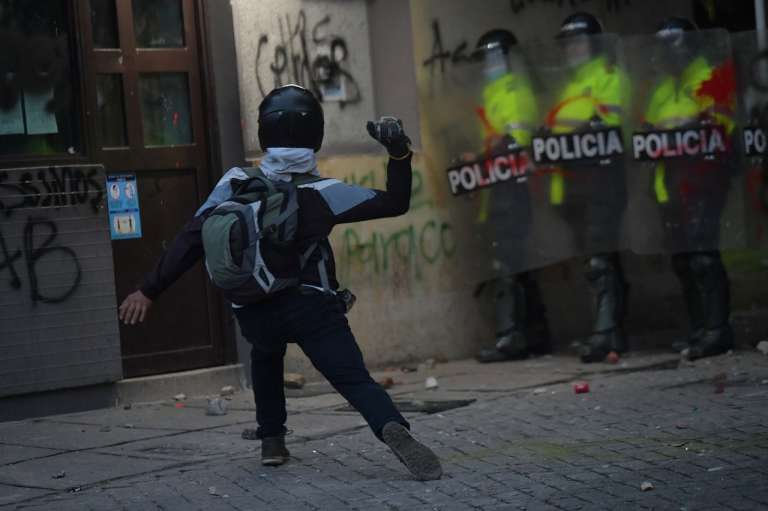 Un hombre de espaldas lanza una piedra.