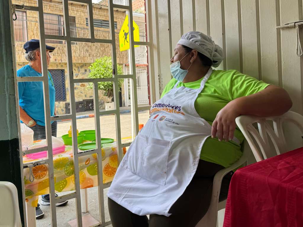 Lucy Uribe, tras terminar de cocinar el almuerzo, se sienta a atender a los clientes que piden el almuerzo para llevar a través de una rendija.