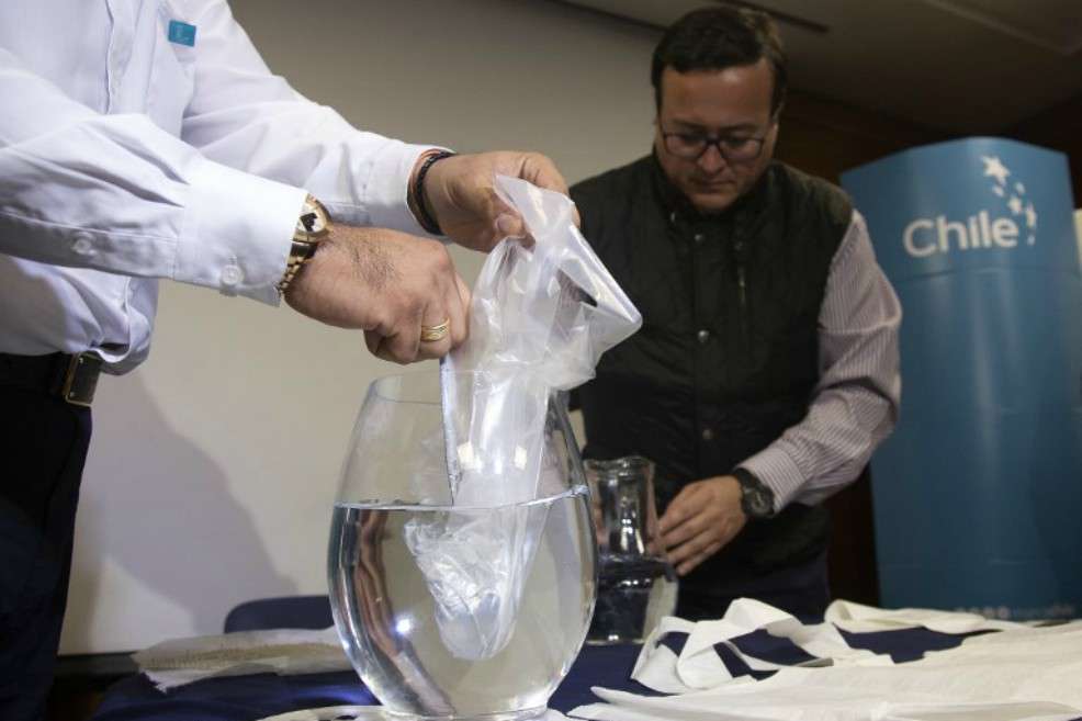 Los ingenieros Roberto Astete (izquierda), y Christian Olivares, durante la rueda de prensa en la que demostraron las propiedades de sus bolsas plásticas solubles en agua y que no contaminan. / AFP