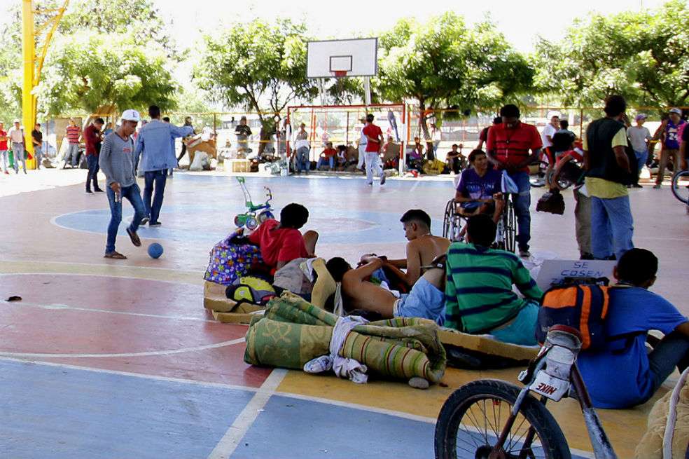 Un grupo de venezolanos que se tomó un polideportivo de un barrio de Cúcuta mientras que decenas de colombianos protestan en contra. / EFE