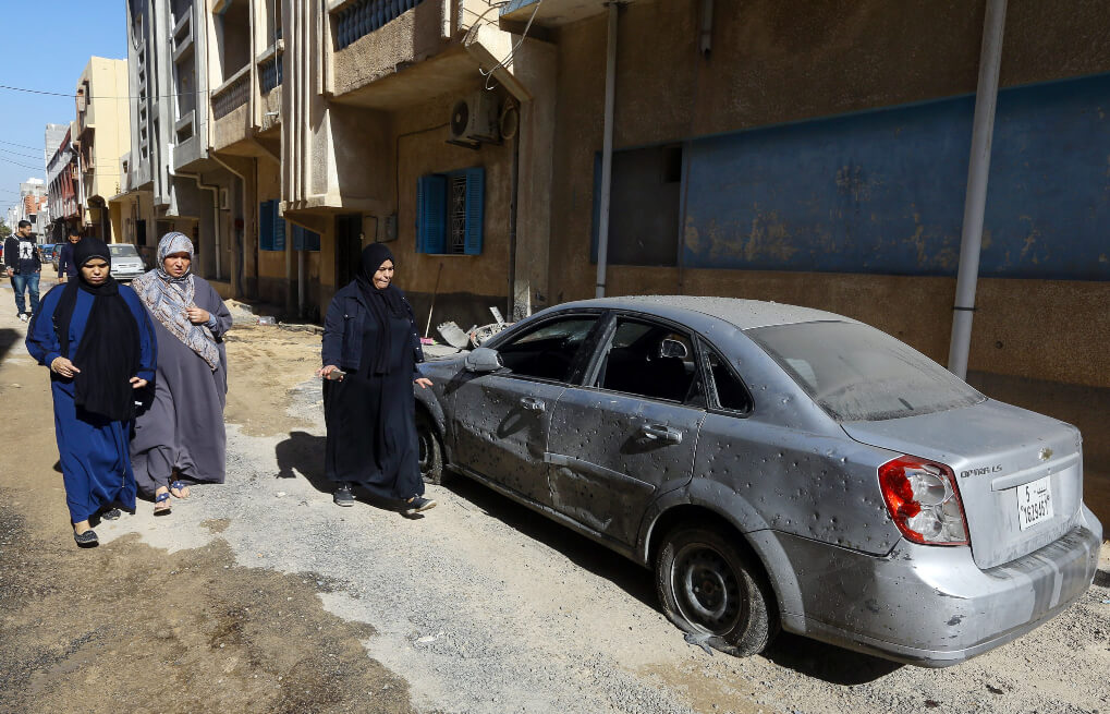 Mujeres libias pasan junto a un automóvil dañado luego de la explosión de un cohete en el distrito meridional de Tripoli de Hadhba al-Badri, el 28 de enero de 2020.
/ AFP