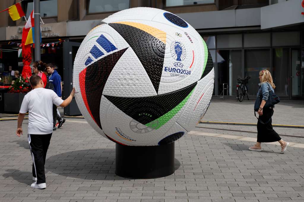 GELSENKIRCHEN, 18/06/2024.- Un niño observa este martes un balón gigante que decora las calles del centro de Gelsenkirchen, donde se celebrará el próximo jueves el España-Italia en el marco de la Eurocopa. EFE/ Alberto Estevez