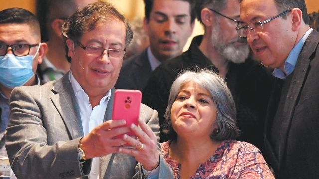 Colombian presidential left-wing candidate Gustavo Petro (C) takes a selfie picture with a supporter during a meeting in Bogota, on June 17, 2022. Petro will face Rodolfo Hernandez in June 19 presidential election. (Photo by DANIEL MUNOZ / AFP)