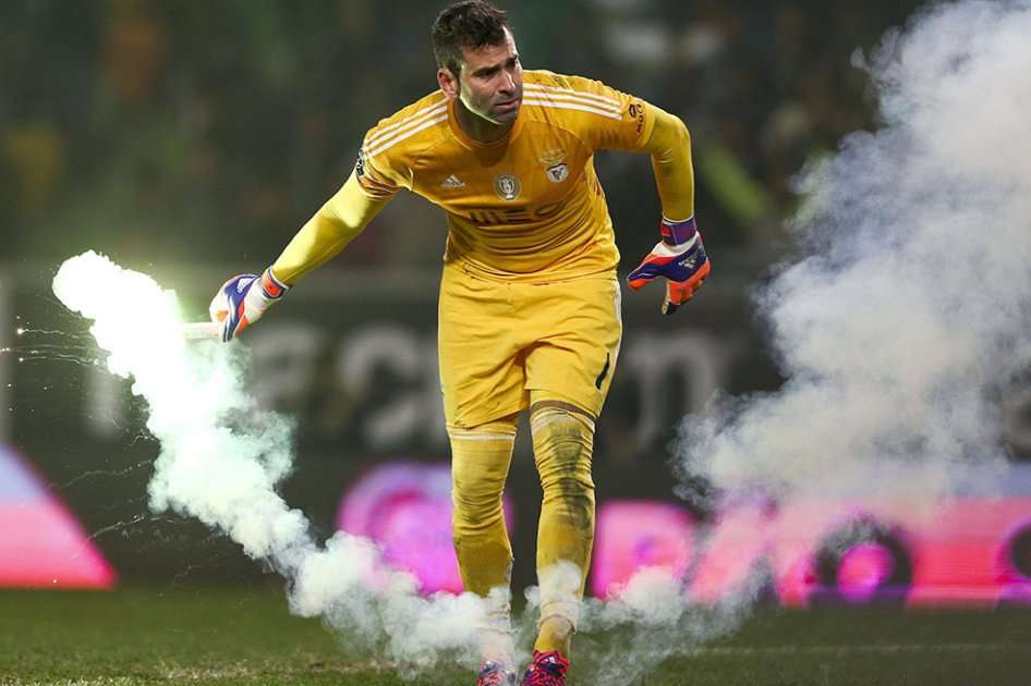 Portero del Sporting de Lisboa retira una bengala lanzada desde las gradas. Foto: AFP