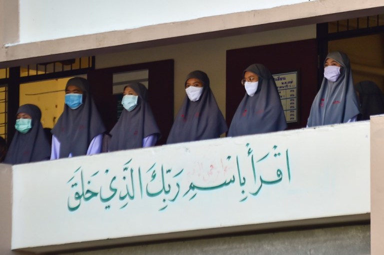 Un grupo de estudiantes musulmanas usan máscaras faciales en la Escuela, en frente de un letrero que dice: "Lee, en el nombre del Señor que te creó".