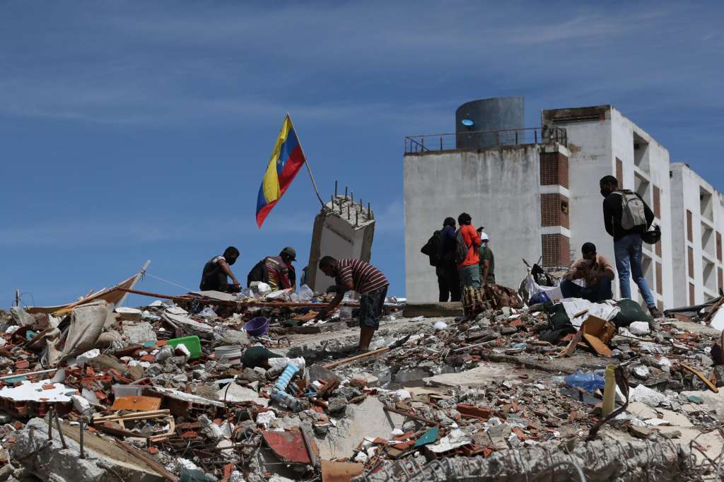 AME6182. LA GUAIRA (VENEZUELA), 30/06/2026.- Personas caminan sobre escombros de edificaciones destruidas este martes, en La Guaira (Venezuela). EFE/ Raúl Martínez