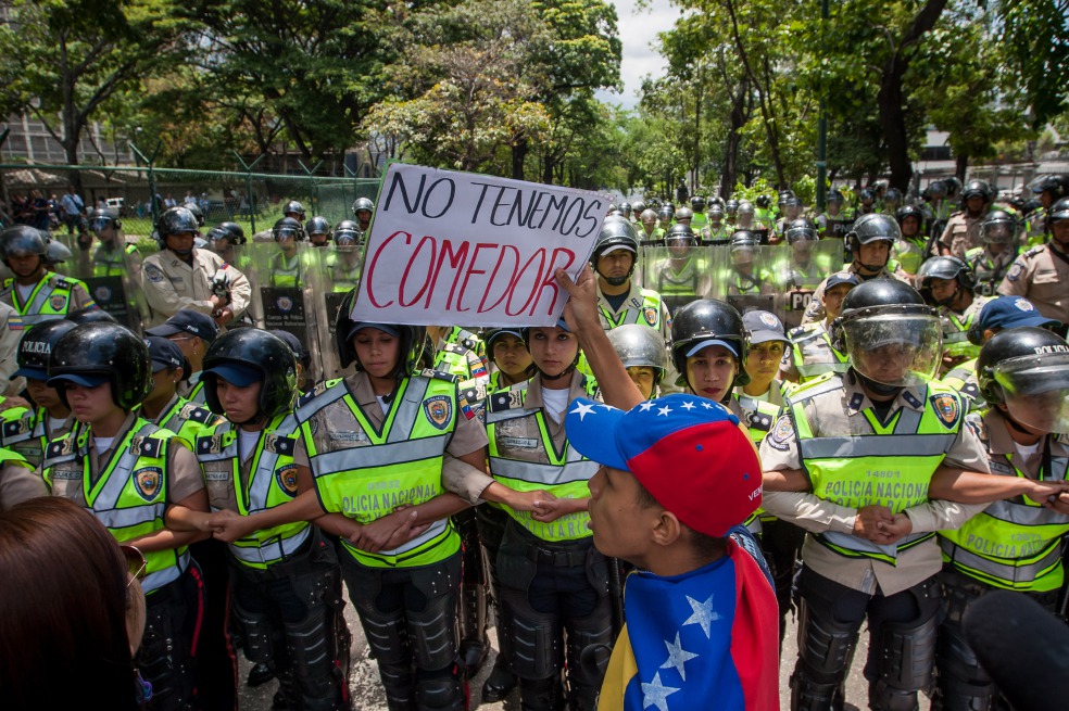 Un estudiante protesta frente a los miembros de la Policía Nacional Bolivariana (PNB) en una marcha por la crisis de las universidades públicas. / EFE
