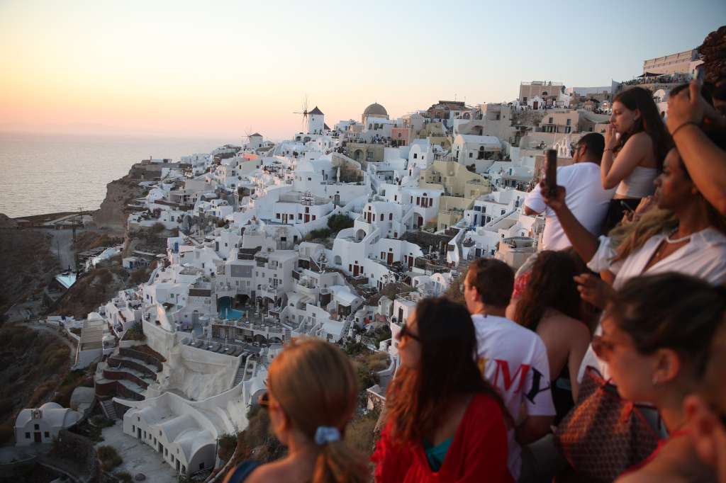 TOPSHOT - Tourists wait for the sunset in the village of Oia on the Greek island of Santorini on July 20, 2024.