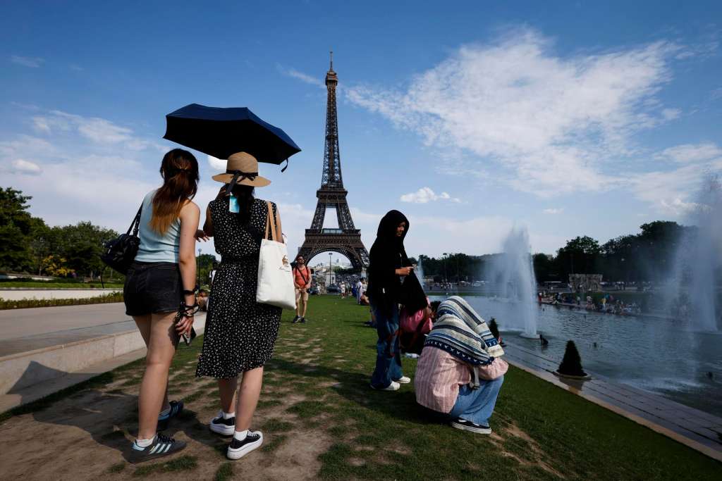 Paris (France), 20/06/2026.- Women shelter from the heat under an umbrella at the Trocadero Fountain by the Eiffel Tower, in Paris, France, 20 June 2026. An intense heatwave is gripping Western and Central Europe, pushing temperatures far above seasonal norms for mid-June. (Francia) EFE/EPA/YOAN VALAT
