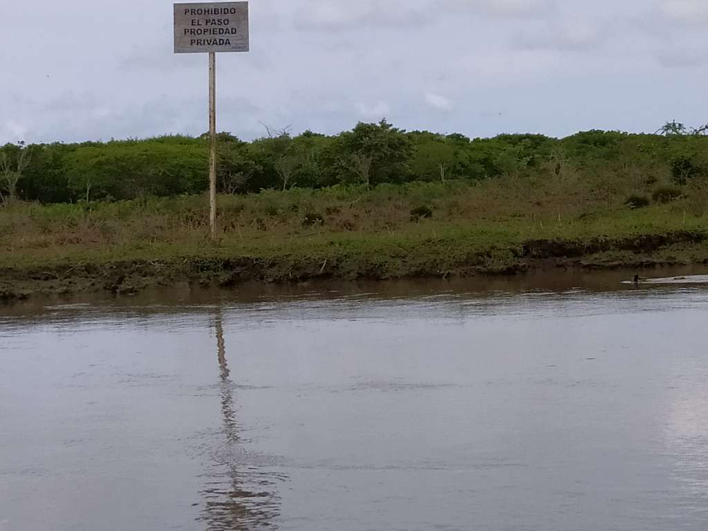 Un tramo del Canal del Dique. Aledaño a la ribera hay un predio con el aviso "Propiedad privada"