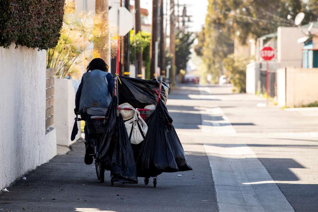 Inglewood (United States), 10/02/2022.- Johnny, a man experiencing homelessness, collects cans and plastic bottles that he stocks in the cart he is pulling with his bike on a street close to SoFi Stadium, in Inglewood, California, USA, 10 February 2022. The surroundings of the stadium have been cleaned and people experiencing homelessness moved from their camps close to the venue ahead of the Super Bowl on Sunday, 13 February. (Estados Unidos) EFE/EPA/ETIENNE LAURENT
