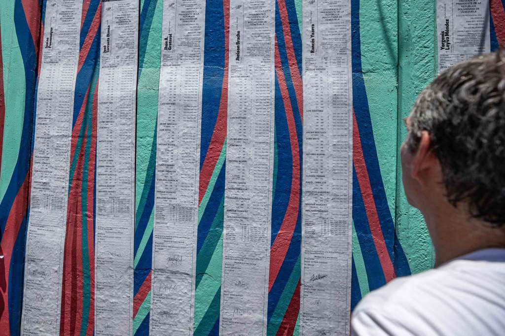 AME7680. CARACAS (VENEZUELA), 03/08/2024.- Una persona observa un collage con actas del Centro Nacional Electoral durante la concentración convocada por la líder opositora María Corina Machado este sábado, en Caracas (Venezuela). Alrededor de un centenar de ciudadanos venezolanos se concentraron este sábado frente a la embajada de su país en Santo Domingo para manifestar su apoyo al candidato opositor Edmundo González Urrutia, al que dan por ganador de las elecciones presidenciales del pasado 28 de julio.Coincidiendo con las movilizaciones convocadas en Venezuela para protestar por los resultados de las presidenciales brindados por el Consejo Nacional Electoral (CNE), según el cual fue reelegido el presidente Nicolás Maduro, venezolanos afincados en República Dominicana se apostaron frente a la sede diplomática portando banderas y carteles, y entonando consignas en apoyo al opositor. EFE/ Henry Chirinos