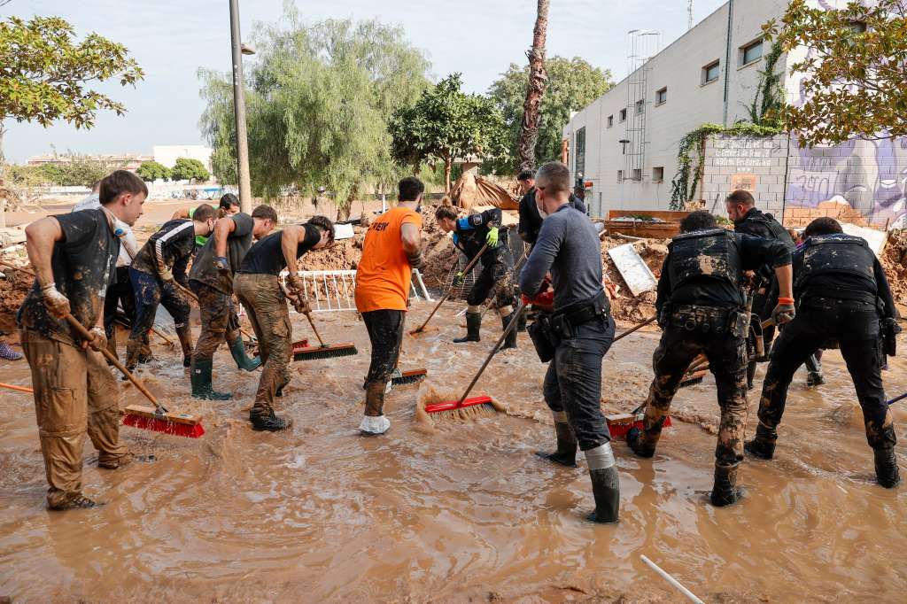 PAIPORTA (VALENCIA), 05/11/2024.- Voluntarios y fuerzas de seguridad trabajan para despejar una calle de Paiporta, este martes. Una semana después del paso de la dana, varios de los pueblos más afectados siguen "en shock" y con grandes necesidades, más allá de comida o productos de limpieza y desescombro, a pesar de la ayuda de los miles de voluntarios y el aumento de efectivos de la UME, ejército, bomberos y policías. EFE/ Manuel Bruque