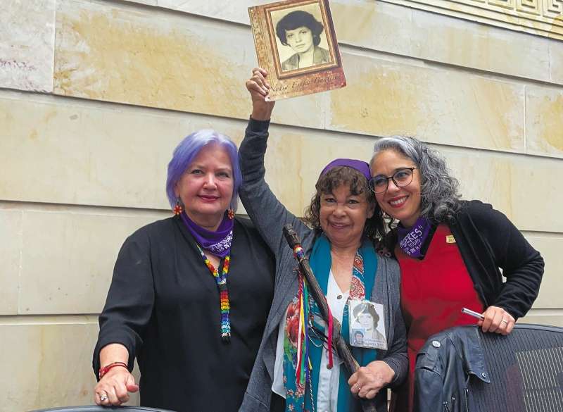 Yannette Bautista (centro), cabeza de la Fundación Nydia Érika Bautista, celebra la aprobación de la Ley de mujeres buscadoras con un bastón de mando indígena y la foto de su hermana, desaparecida en 1987. / Cortesía
