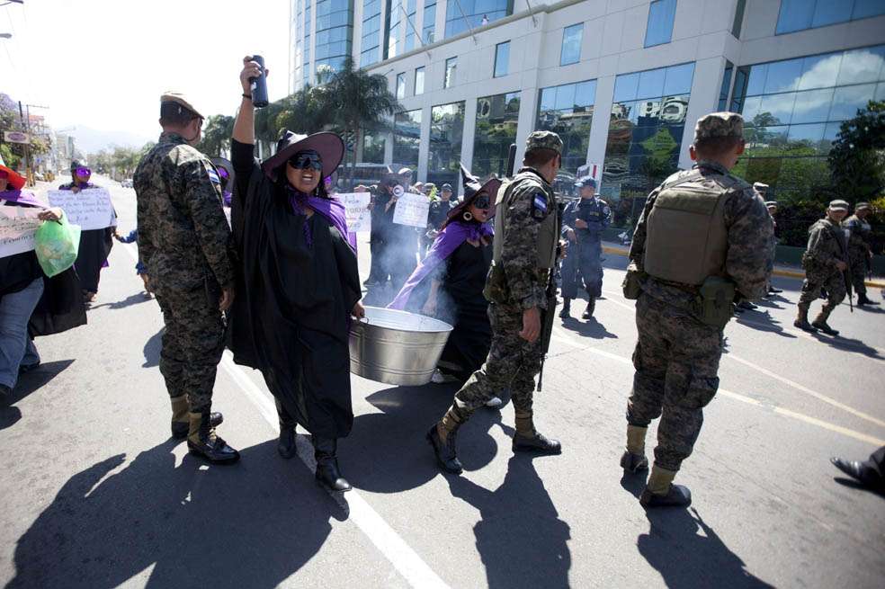 Mujeres de organizaciones feministas realizan la representación de un ritual de brujas frente a la entrada de la Casa Presidencial en Tegucigalpa, exigiendo al Gobierno la investigación de feminicidios. / EFE