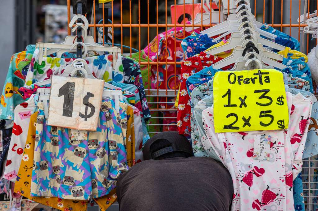 AME524. CARACAS (VENEZUELA), 15/08/2024.- Un vendedor de ropa acomoda prendas en su puesto este miércoles, en el Boulevard Sabana Grande en Caracas (Venezuela). Tras una breve pausa poselectoral, Venezuela ha reanudado su actividad económica sin grandes alteraciones a pesar de la actual coyuntura -marcada por protestas y cuestionamientos por el anunciado triunfo de Nicolás Maduro y acusaciones de fraude-, aunque con incertidumbre y el riesgo de un "mayor" aislamiento internacional, según expertos. EFE/ Henry Chirinos